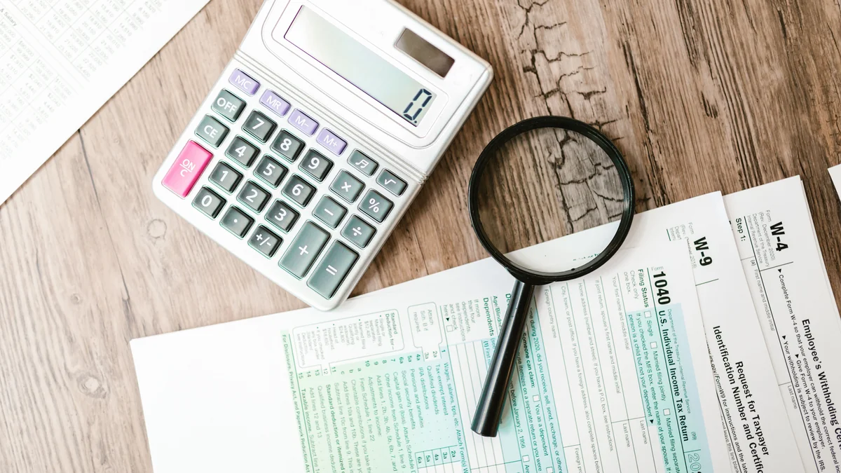 Calculator and IRS tax forms on a wooden desk, representing subsidy and income paperwork